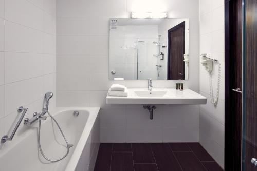 a white bathroom with a sink and a bath tub at Van der Valk Hotel Arnhem in Arnhem