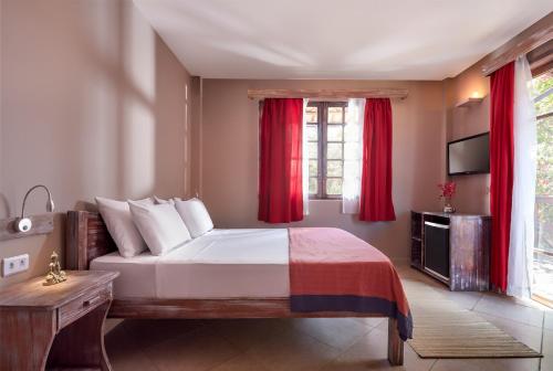 a bedroom with a large bed with red curtains at All Blue in Jericoacoara