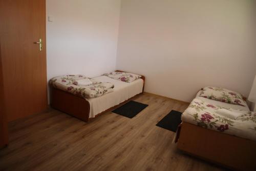 two beds in a small room with wooden floors at Osrodek Wypoczynkowy " BIESZCZADY" in Myczkowce