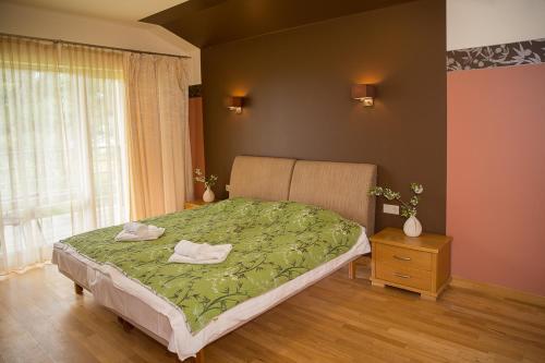 Un dormitorio con una cama con sábanas verdes y una ventana en Beach Guesthouse Lenkas, en Saraiķi