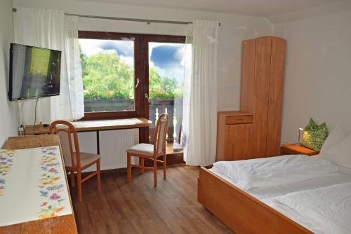 a bedroom with a bed and a desk and a window at Waldgasthof Altersbach in Waldkirch