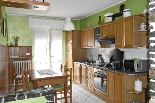 a kitchen with wooden cabinets and a table in it at casa vacanza DolceVita in Averara