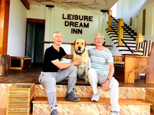 
a man sitting on a bench with a dog at Leisure Dream Inn in Ella
