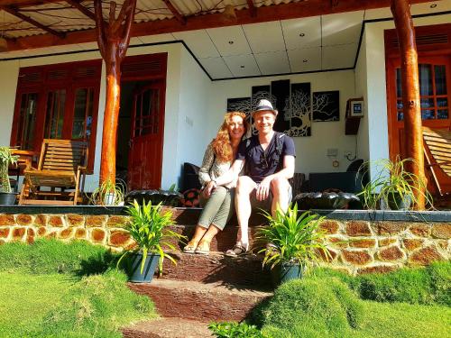 a man and a woman sitting in front of a house at Leisure Dream Inn in Ella