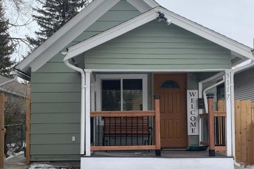 a small green house with a porch and a door at Dillon Ave Homes in Cheyenne