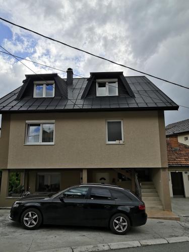a black car parked in front of a house at Apartman Jela in Nova Varoš