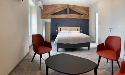 a bedroom with a bed and two chairs and a table at Hotel - Restaurant Les 3 Piliers in Le Boupère