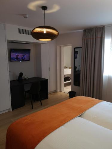 a bedroom with a bed and a desk with a television at B&B Atuatuca in Tongeren