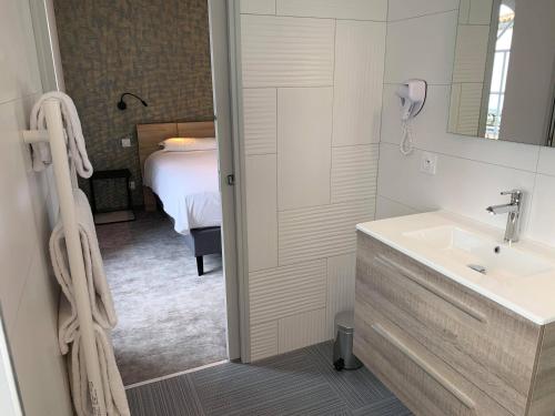 a bathroom with a sink and a bedroom with a bed at Hotel - Restaurant Les 3 Piliers in Le Boupère