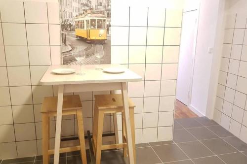 una pequeña mesa con dos taburetes y un tranvía amarillo en InLoveApartments - Typical Alfama Balcony, en Lisboa