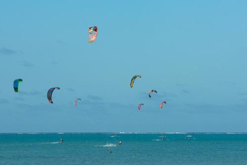 a group of people flying kites in the ocean at Hakuna Majiwe Beach Lodge in Paje