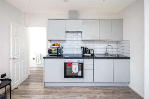 a kitchen with white cabinets and a sink at Skyline Serviced Apartments - Vauxhall in London
