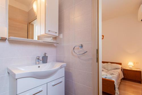 a white bathroom with a sink and a bedroom at Room Laudina in Cres