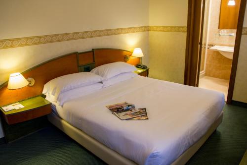 a hotel room with a bed with a magazine on it at Best Western Plus Soave Hotel in San Bonifacio