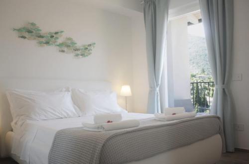 a bedroom with a white bed with a window at Wind Rose Apartments in Nago-Torbole
