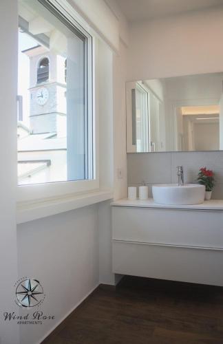 a white bathroom with a sink and a window at Wind Rose Apartments in Nago-Torbole