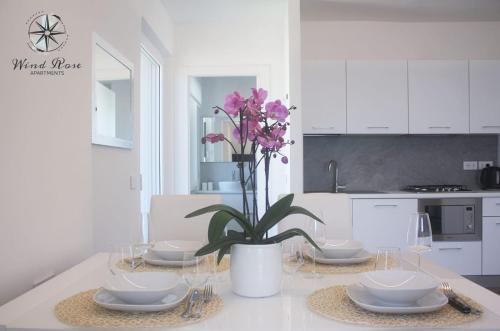 una cocina blanca con una mesa con gafas y una planta en Wind Rose Apartments, en Nago-Torbole