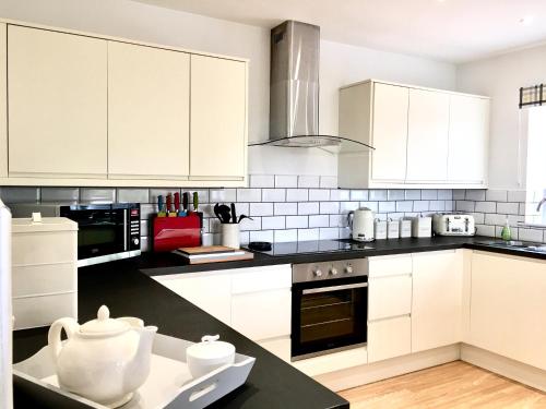 a kitchen with white cabinets and black counter tops at Blackdown Views - New 6 Bedroom Eco House in Dunkeswell