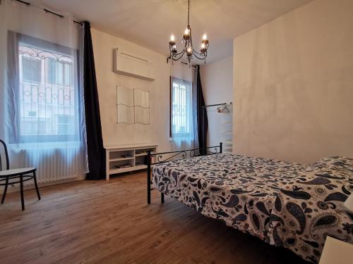 a bedroom with a bed and a table and two windows at Ca' delle Furlane in Venice