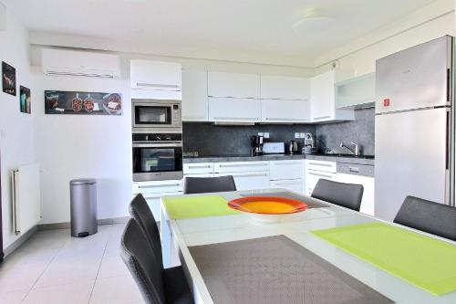 une cuisine avec des armoires blanches et une table et des chaises dans l'établissement O de mer D101, à La Ciotat