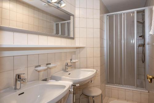 Baño blanco con lavabo y espejo en Landhaus Haid, en Seefeld in Tirol