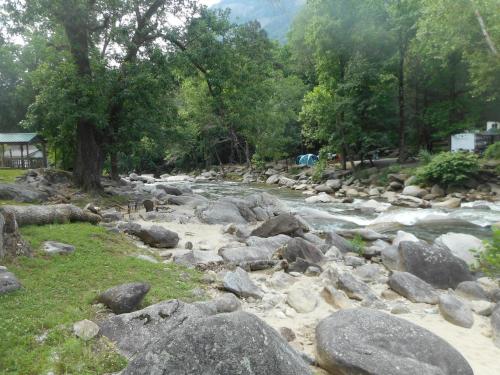 a river with rocks and trees in the background at The Evening Shade River Lodge and Cabins in Chimney Rock