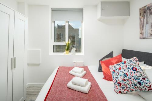 a white room with a bed with towels on it at Skyline Serviced Apartments - Vauxhall in London