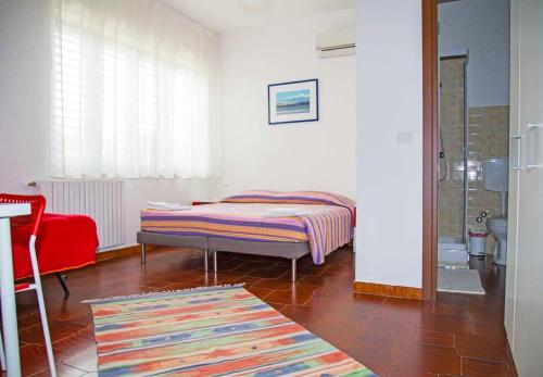 um pequeno quarto com uma cama e uma cadeira vermelha em La Casa del Lago Pergusa Lake Home em Pergusa