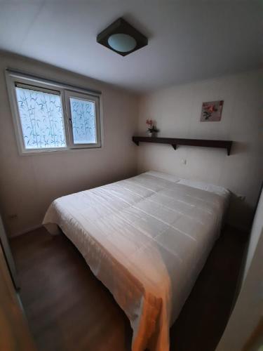 a bedroom with a large white bed with a window at Chalet de Huismus in Rijs