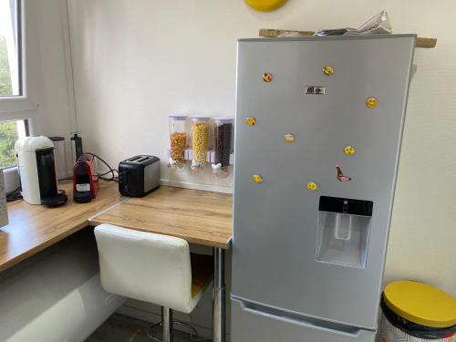Un réfrigérateur blanc est installé à côté d'un bureau en bois. dans l'établissement Your Place in LH, au Havre
