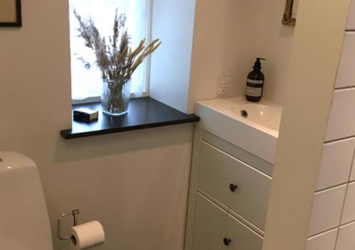 a bathroom with a sink and a vase of flowers at Svenskebakken Bed & Breakfast in Roskilde