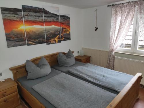 um quarto com uma cama com três pinturas na parede em Ferienhaus Schwarzwald Seewald Erzgrube Badesee 100% Natur em Seewald
