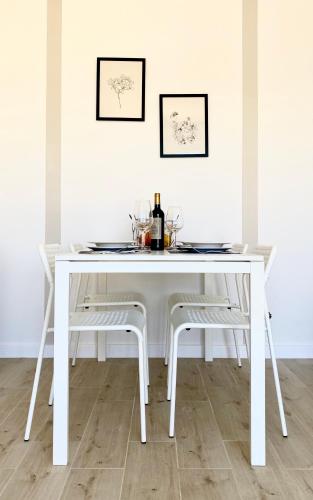 a white dining table with two chairs and wine glasses at Resto domki letniskowe in Sarbinowo