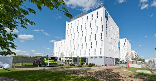 a large white building in a parking lot at ibis budget Muenchen City Olympiapark in Munich