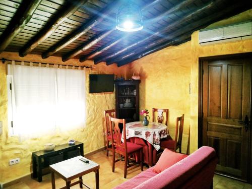 un soggiorno con tavolo e divano rosa di Casa rural La Villa a Miranda del Castañar