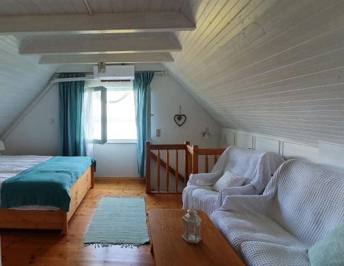 um quarto com uma cama, um sofá e uma janela em Szőlőskert Vendégház Badacsony em Badacsonytomaj