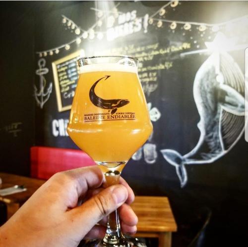 a person holding up a glass of beer at La Baleine Endiablée Microbrasserie in Rivière-Ouelle