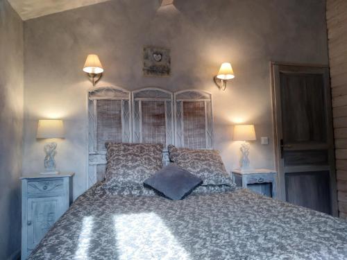 a bedroom with a large bed with two lamps on it at Côté Chapelle in Coursegoules