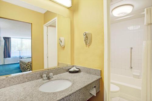 a bathroom with a sink and a toilet and a mirror at Days Inn by Wyndham Alexandria South in Alexandria