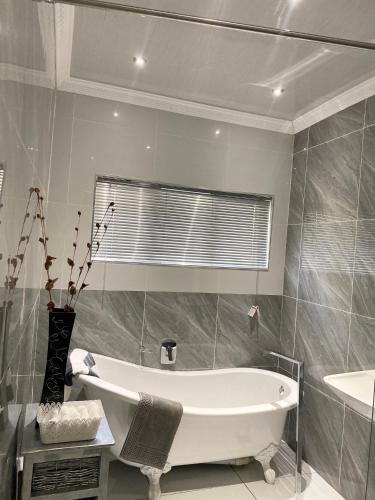a bathroom with a bath tub and a sink at River Valley Guest House in Butterworth