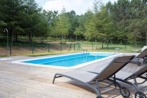 a swimming pool with a chair and a swing at Cabanas da Ulla in Touro