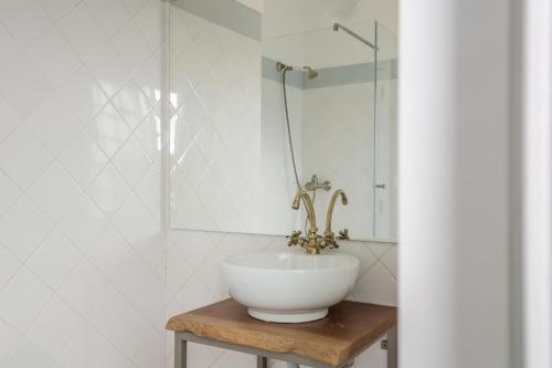 a white sink sitting under a mirror in a bathroom at Sandhi House - Yoga & Wellness in Ericeira