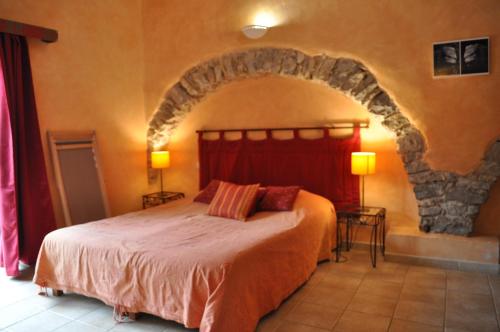 a bedroom with a large bed with a stone wall at Domaine De Blancardy in Moulès-et-Baucels