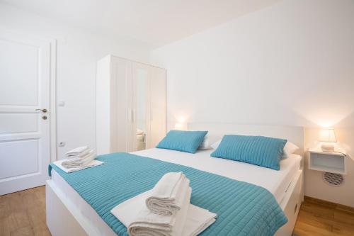 a white bedroom with a bed with towels on it at Villa Brac with pool Bol in Bol