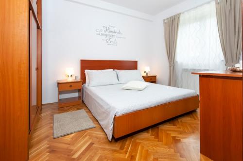 a bedroom with a bed with white sheets and wood floors at Apartments Anamarija in Rovinj