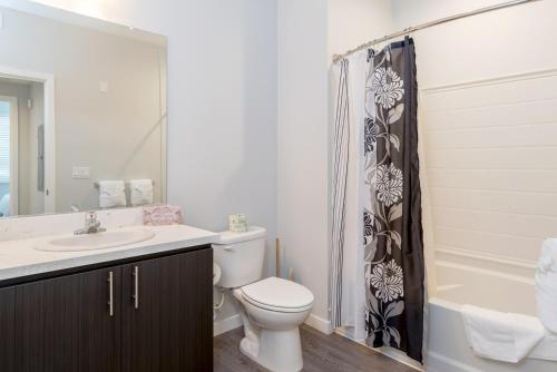 a bathroom with a toilet sink and a shower curtain at Churchill Living at Anton Menlo in Menlo Park