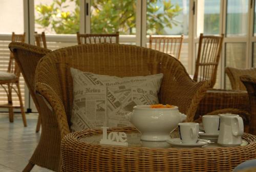 a table with cups and a bowl on a wicker chair at Hotel Arno in Rimini
