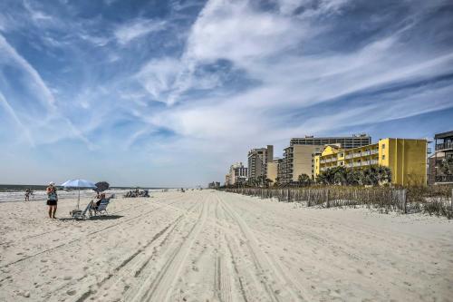 a person standing on a beach with an umbrella at 1 Block to Ocean Shore Condo in Myrtle Beach! in Myrtle Beach