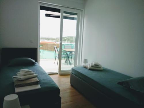 1 Schlafzimmer mit 2 Betten und einer Tür zu einer Terrasse in der Unterkunft SEAVIEW ROGOZNICA in Rogoznica