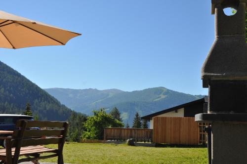 a bench with an umbrella in a yard with mountains at Landhaus Zirben in Bad Kleinkirchheim